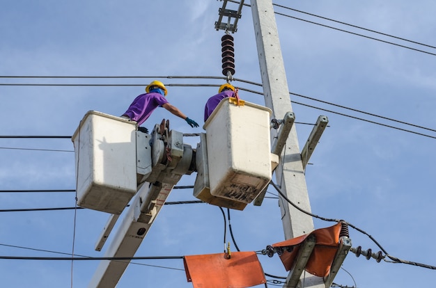 L&#39;elettricista lavora su pali elettrici.