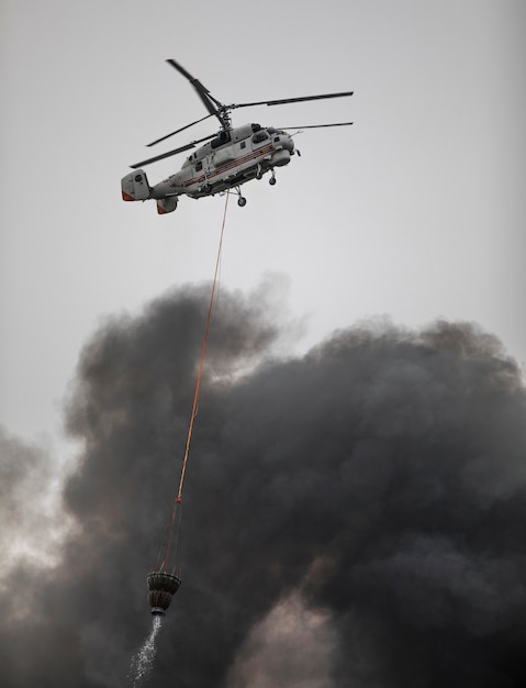 l'elicottero spegne un incendio da un cesto d'acqua