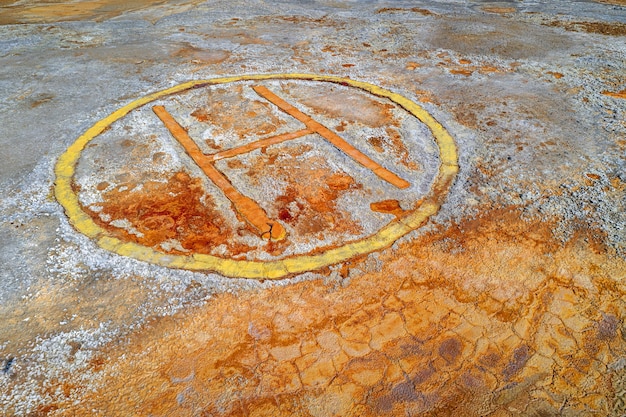 L'eliporto arrugginito firma sopra il terreno contaminato dell'area mineraria abbandonata, sfondo distopico