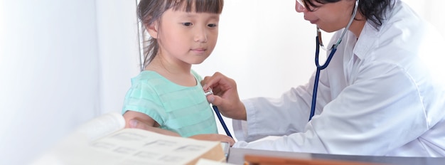 L'esame del medico pediatra ascolta i polmoni una bambina dall'ampio fondo dell'insegna dello stetoscopio.