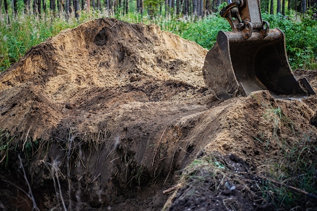 L&#39;escavatore esegue lavori di scavo scavando il terreno con un secchio