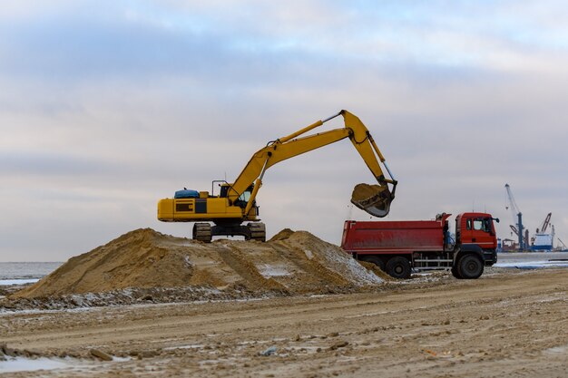 L'escavatore giallo carica la terra nel dumper. La costruzione della strada.