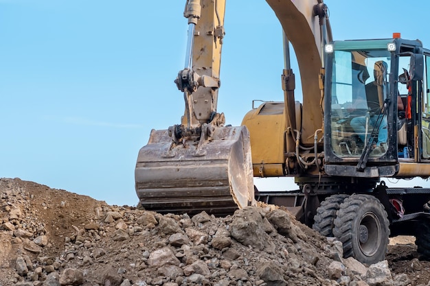 L'escavatore gommato esegue il primo piano dei lavori di costruzione di strade