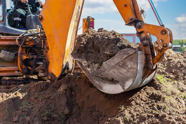 L'escavatore scava una fossa di fondazione profonda. Avvicinamento. Lavori di sterro in un cantiere edile.