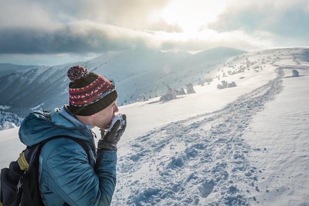 L'escursionista assetato mangia la neve fresca in montagna