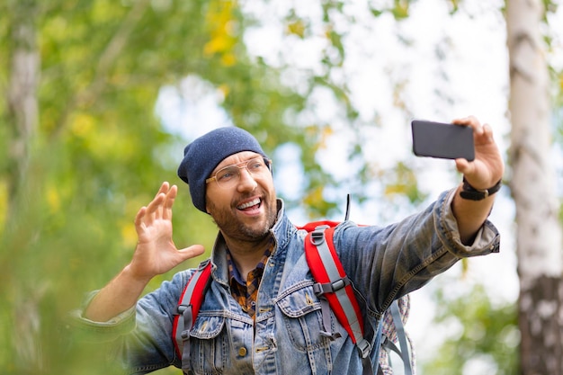 L'escursionista maschio fa un selfie o fa una videochiamata con il cellulare