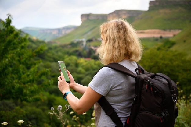 L'escursionista utilizza l'app navigatore gps nello smartphone che cammina in montagna