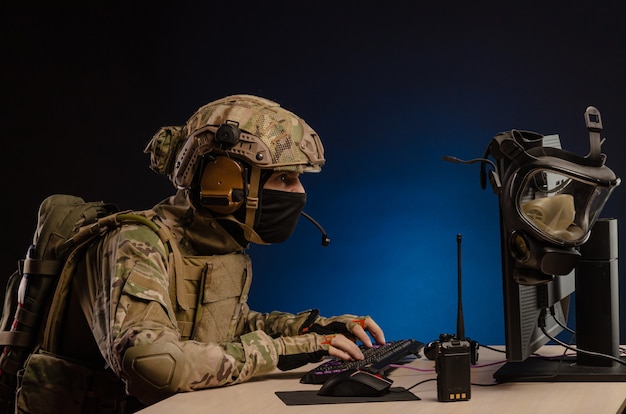 L'esercito in uniforme seduto al computer conduce una guerra informatica