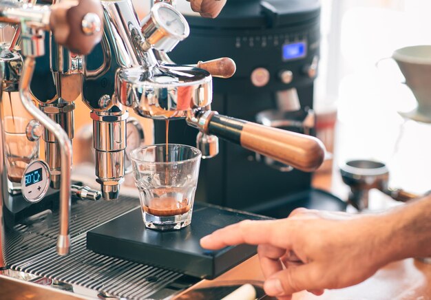 L'espresso viene riempito in un bicchiere da una macchina per caffè espresso con portafiltro Viene utilizzata un'attrezzatura per bilancia di precisione