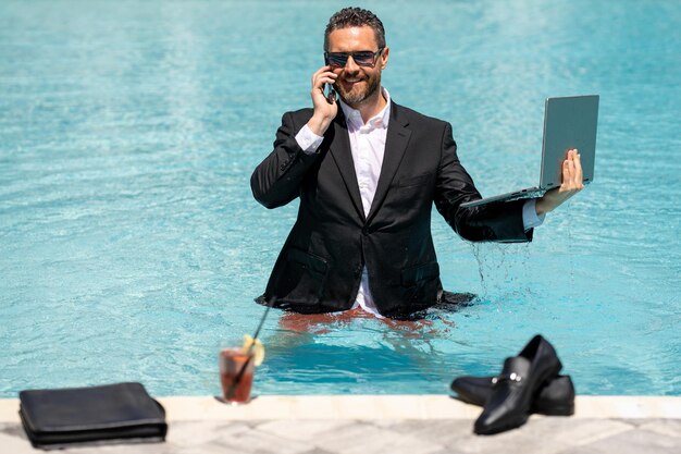 L'estate folle di affari divertimento di affari stile di vita uomo d'affari bello in abito che usa il portatile nel nuoto