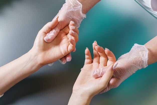 L'estetista esegue un massaggio professionale leggero alle mani dopo la procedura di manicure cura di sé mensile e addizio...