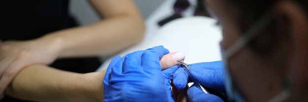 L'estetista taglia le cuticole delle unghie dei clienti nel concetto di cura del corpo del primo piano del processo di manicure del salone