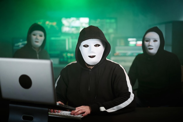 L'hacker mascherato sta utilizzando il computer per organizzare un massiccio attacco di violazione dei dati sui server aziendali