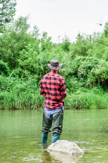 L'hobby è il modo migliore per andare a pesca con la mosca di successo fine settimana estivo pescatore mostra la tecnica di pesca usa la canna attività sportiva hobby pescatore esperto in acqua uomo che cattura pesce uomo pesca a mosca