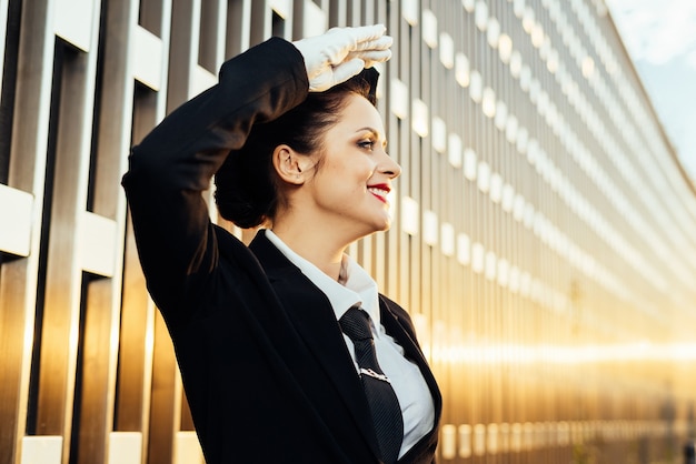 L'hostess di donna felice in uniforme guarda il cielo