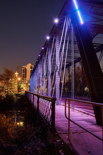 L'immagine del ponte di metallo che conduce in una città è illuminata di viola di notte