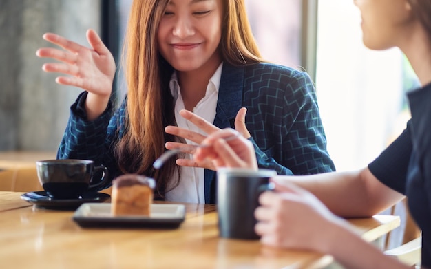 L'immagine del primo piano delle donne si è divertita a mangiare il dessert e a bere il caffè insieme al bar