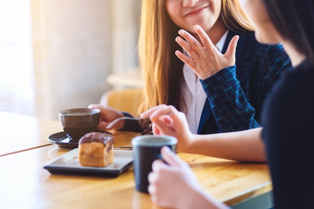 L'immagine del primo piano delle donne si è divertita a mangiare il dessert e a bere il caffè insieme al bar