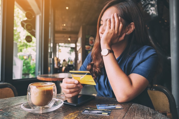 L'immagine del primo piano di una donna asiatica si stressa e si spezza mentre tiene la carta di credito