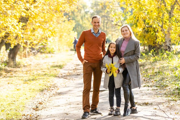 L'immagine della bella famiglia nel parco autunnale, i giovani genitori con un bel bambino adorabile che gioca all'aperto, si divertono nel cortile in autunno, la famiglia felice si gode la natura autunnale.