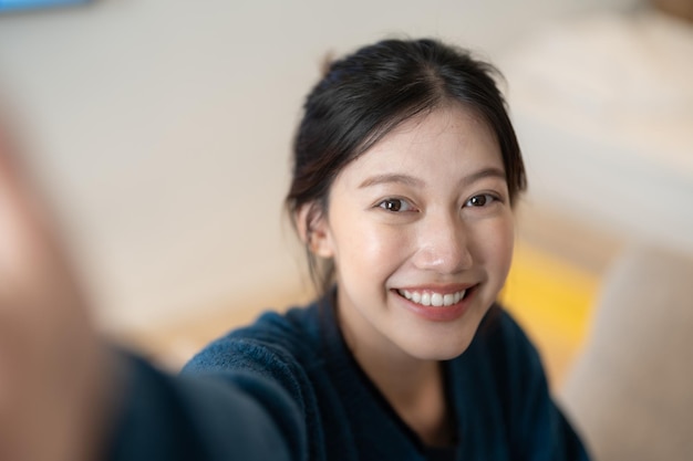 L'immagine della giovane donna asiatica attraente fa il selfie dalla macchina fotografica a casa sua