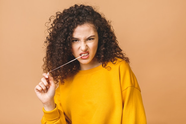 L'immagine di giovane signora attraente si è vestita nella condizione casuale isolata sopra fondo beige che allunga la gomma da masticare.