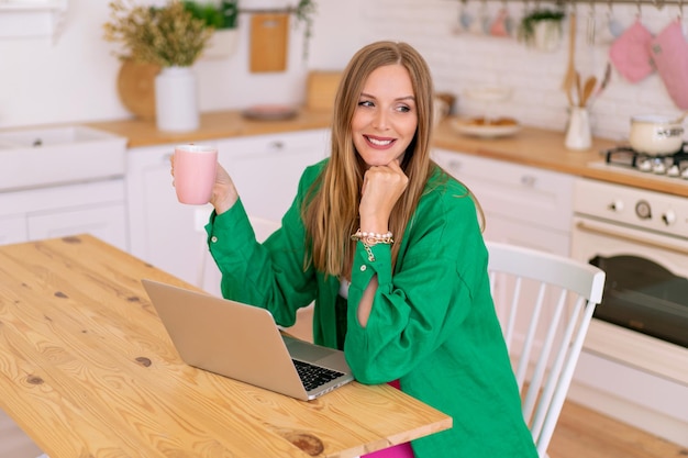 L'immagine di stile di vita indoor di una donna blogger alla moda tocca il suo laptop, il concetto di home office.