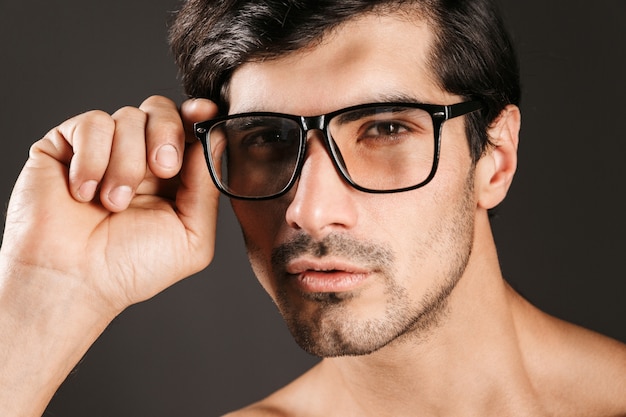 L'immagine di un giovane bello concentrato serio ha isolato gli occhiali da vista.