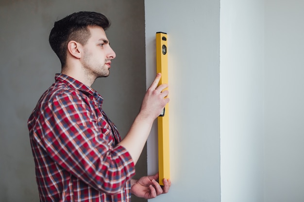 L&#39;immagine di un giovane uomo sicuro è in possesso di un righello, una cintura di strumenti di impiccagione