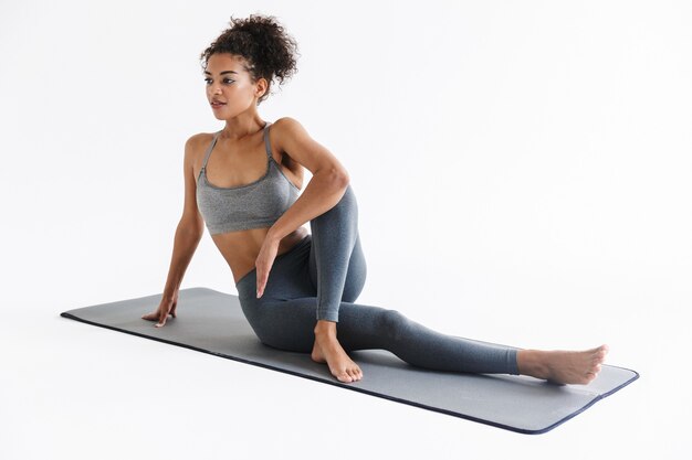 L'immagine di una bellissima giovane donna africana di fitness sportivo più forte fa esercizi isolati sul muro bianco.