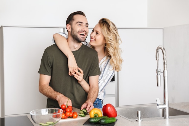 L'immagine di una giovane coppia amorosa felice che posa alla cucina a casa che cucina ha un abbraccio della prima colazione.