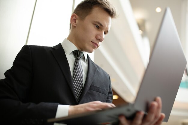 L'immagine di uno studente serio che lavora al laptop, vestito con un abito nero in un centro commerciale