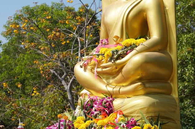 L'immagine dorata del Buddha ha molte persone che portano fiori per adorare