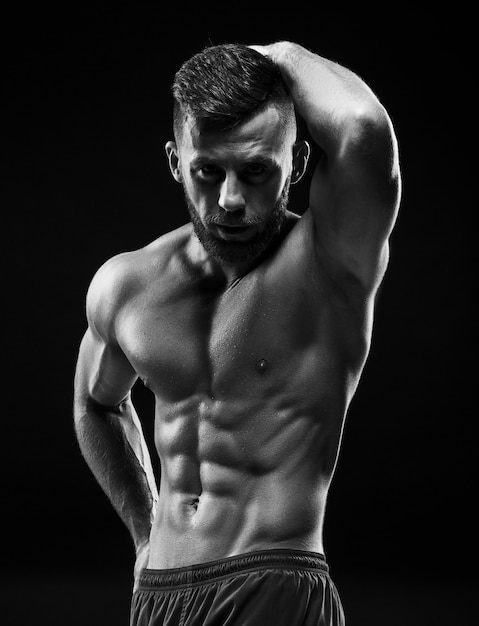 L'immagine incolore del torso di attraente body builder maschio su sfondo nero studio.