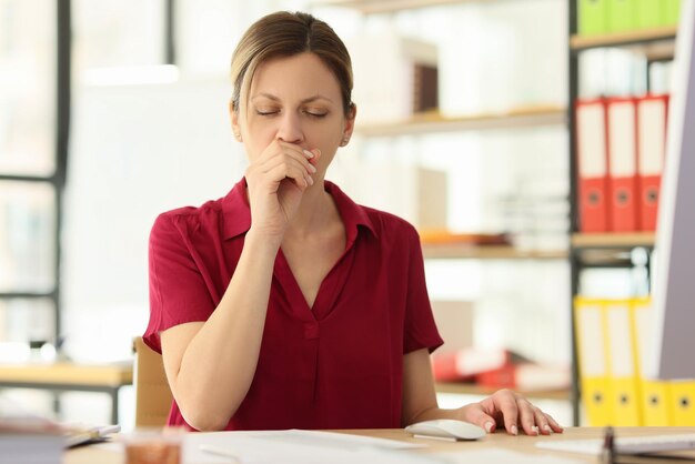 L'impiegata tossisce seduta alla scrivania nell'ufficio aziendale closeup donna con sintomi influenzali funziona
