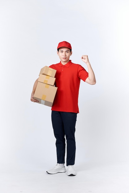 L'impiegato del ragazzo delle consegne professionale con berretto rosso Tshirt uniforme da lavoro lavora come corriere del commerciante tiene i muscoli della scatola di cartone