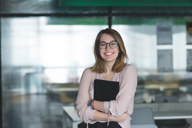 L'impiegato di concetto felice della ragazza sta con una compressa in sue mani e sorrisi.