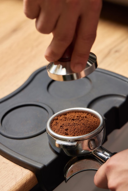 L'impiegato part-time della caffetteria dell'uomo asiatico prepara il caffè caldo nella fabbricazione della mano del barista maschio della macchina del caffè