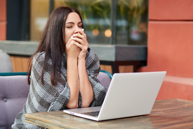 L'imprenditore femminile assonnato stanco sbadiglia davanti al computer portatile moderno, la vita per feedback, lavora al rapporto di affari