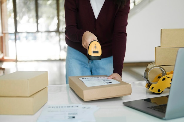 L'imprenditore online femminile esegue la scansione dell'etichetta di spedizione sul pacco