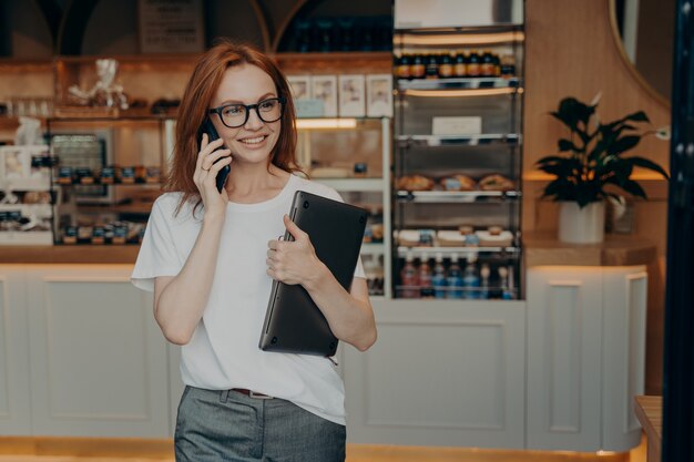 L'imprenditrice con i capelli rossi ha una conversazione telefonica che tiene un laptop