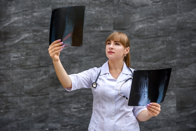 L'infermiera dell'allievo in uniforme medica esamina i raggi x delle fotografie del piede. concetto medico