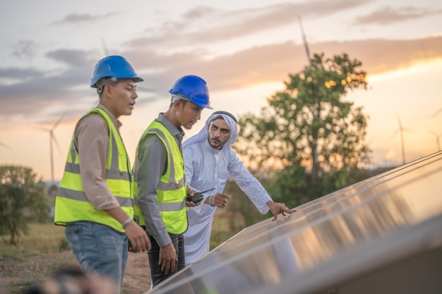 L'ingegnere ispeziona la costruzione del pannello solare o della cella fotovoltaica mediante dispositivo elettronico Energia rinnovabile industriale dell'operaio di fabbrica di energia verde che lavora sul tetto della torre