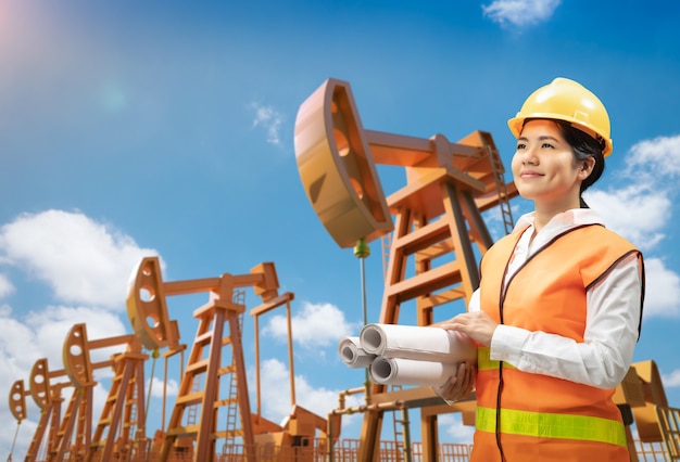 L'ingegnere o il tecnico della piattaforma petrolifera indossa un casco di sicurezza e un giubbotto riflettente con pompa del petrolio greggio
