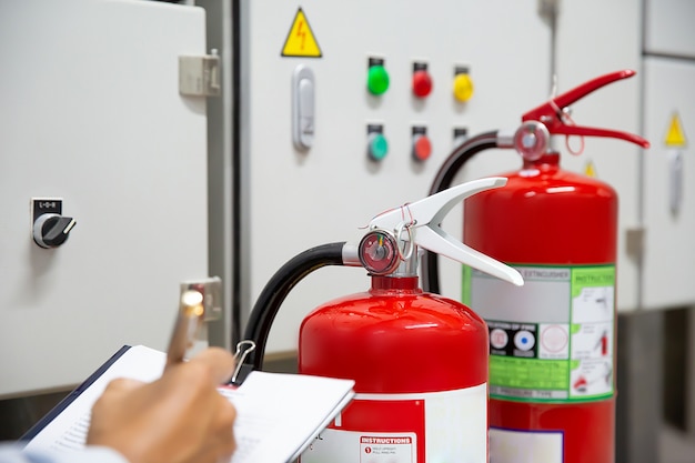 L'ingegnere sta controllando e ispezionando un estintore nella sala di controllo del fuoco per sicurezza.