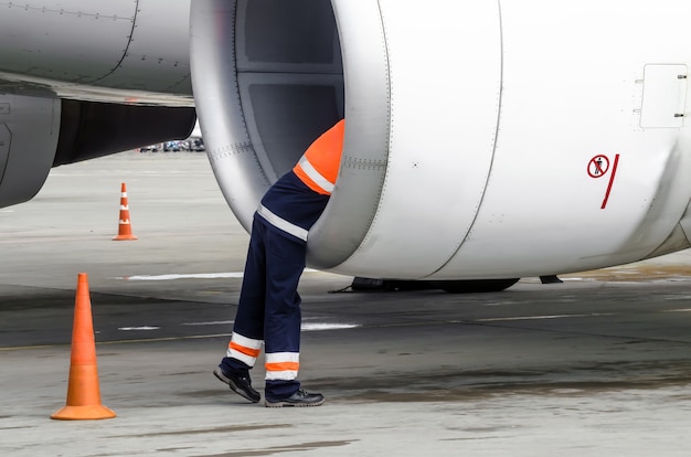 L'ingegnere tecnico umano controlla la pala dell'aereo del motore a turbina dopo il viaggio e lo psodki nel parcheggio dell'aeroporto.