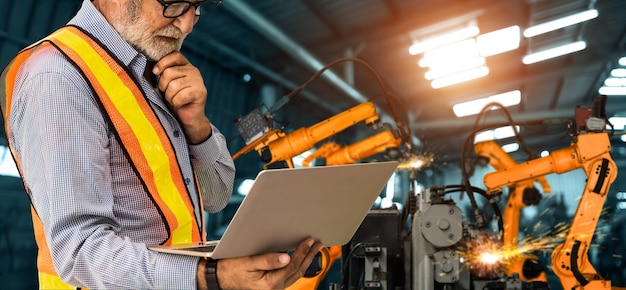 L'ingegnere utilizza un software robotico avanzato per controllare il braccio robotico industriale in fabbrica