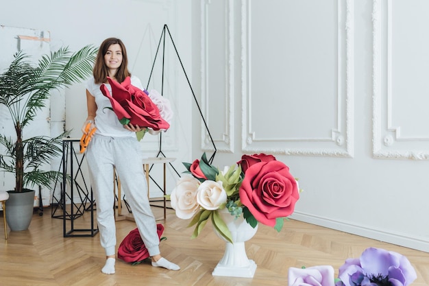 L'inquadratura orizzontale del fiorista femminile realizza bellissimi bouquet con fiori artificiali in una spaziosa sala si prepara per l'evento festivo ha soddisfatto l'espressione Decorazione della gente e concetto floreale