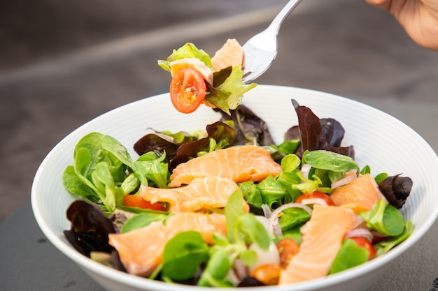 L'insalata di salmone fresca con pomodori dolci, aglio sottaceto, cipolle e spinaci è una dieta sana per ogni pasto.