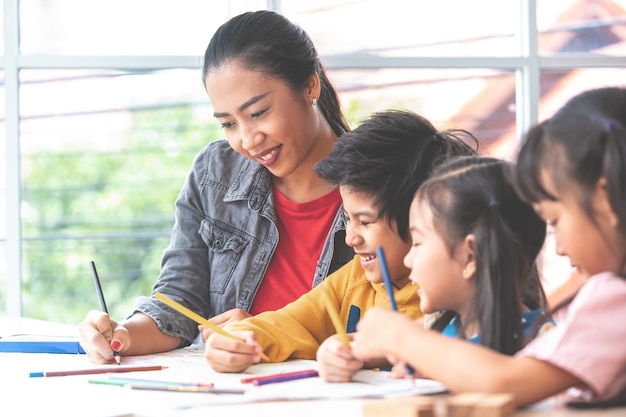 L&#39;insegnante asiatico sta insegnando ai bambini nell&#39;aula della scuola materna